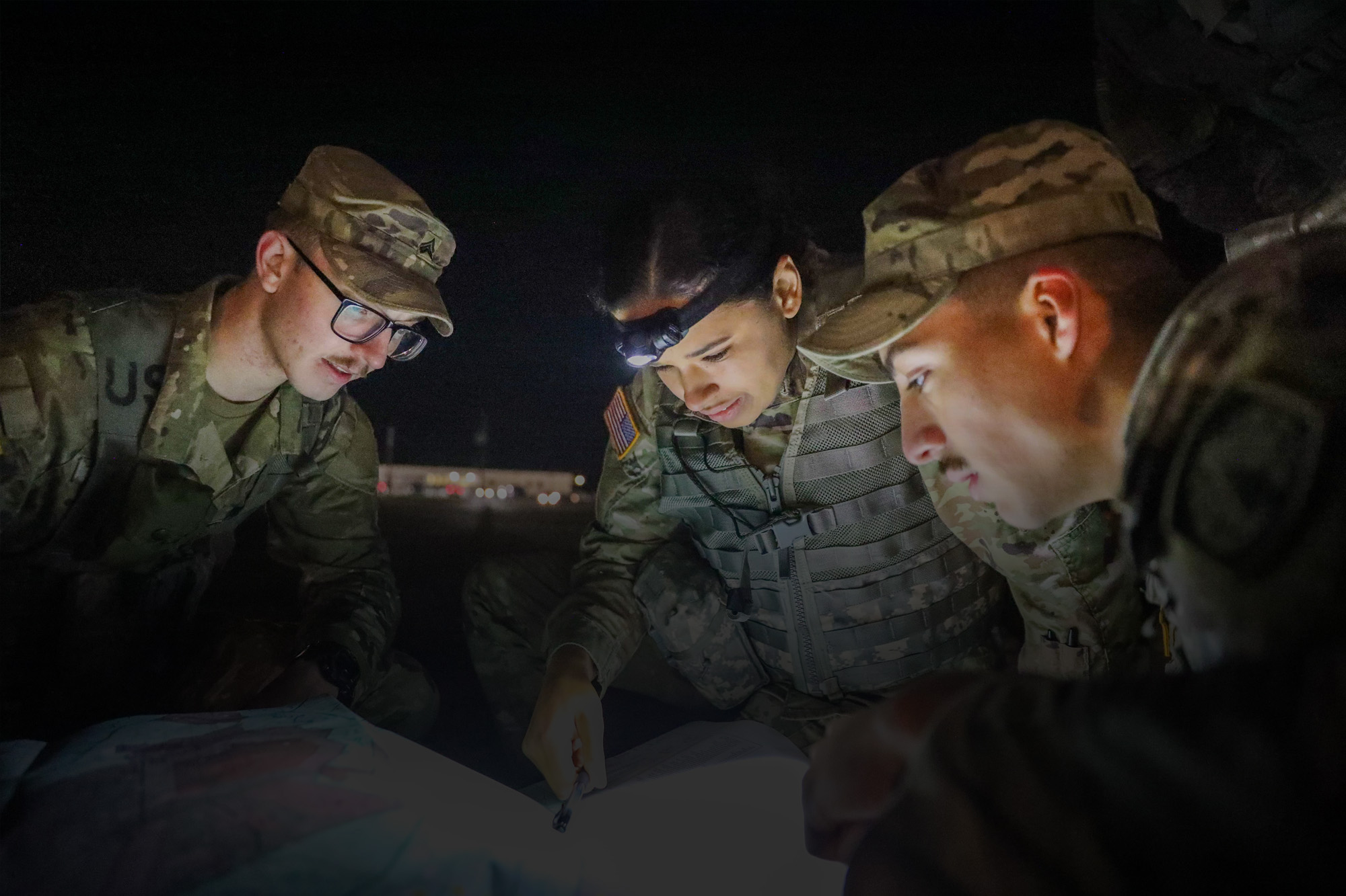 Three soldiers reading a map in the dark