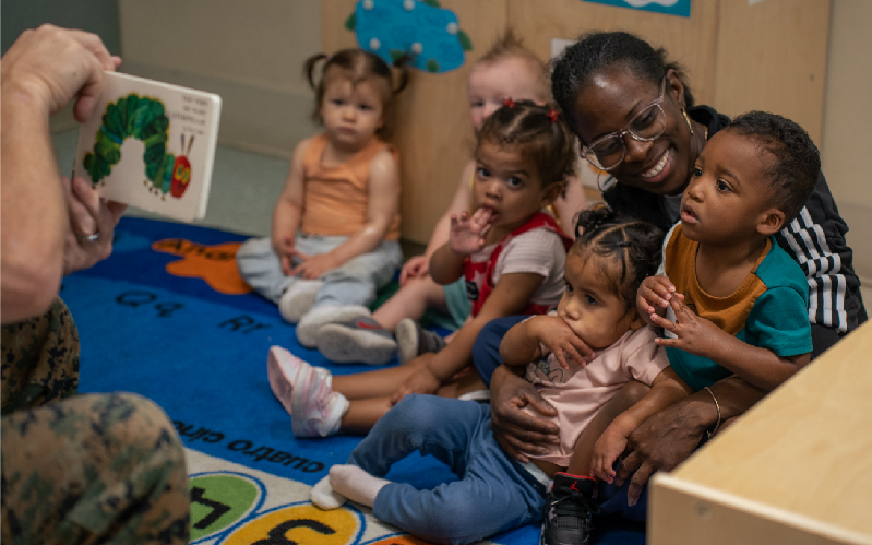 Mother holding child in school room with other children