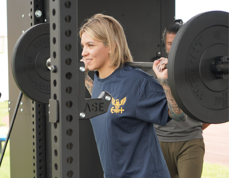 Navy sailor doing squats on a weight bench